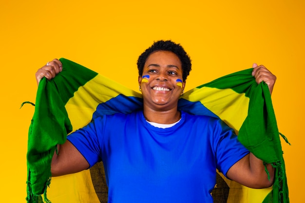 Supporter brésilien Fan brésilienne célébrant le football ou le match de football sur fond jaune Couleurs du Brésil