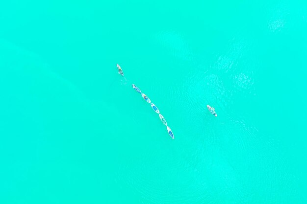 Surf de SUP. Image aérienne de personnes pagayant sur des planches sup et de l'eau turquoise.