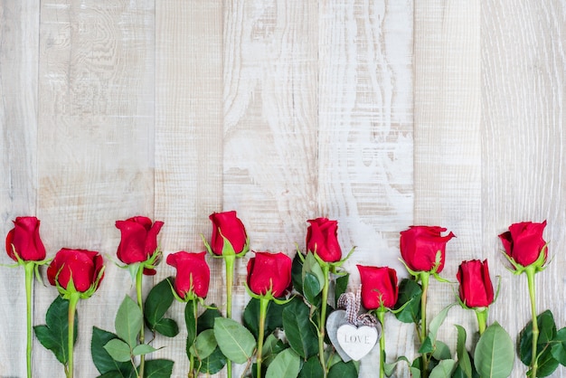 surface en bois clair avec cadre de roses et coeurs en bois