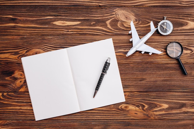 Sur une surface en bois une feuille de papier blanche et un stylo un avion et un concept de voyage de boussole
