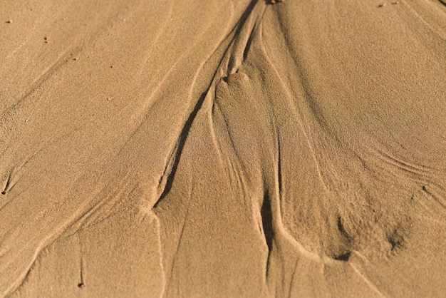 La surface du sable. Les stries de l'eau sur la plage. La vue d'en haut. Fond texturé beige.