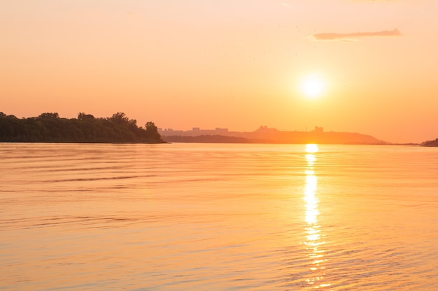 Surface de l'eau calme avec ciel coucher de soleil jaune et soleil à travers les nuages au-dessus de l'eau et du ciel de méditation