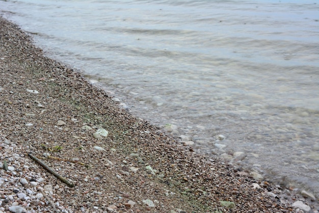 Une surface d'eau claire sur la côte avec une plage de galets par temps nuageux et pluvieux