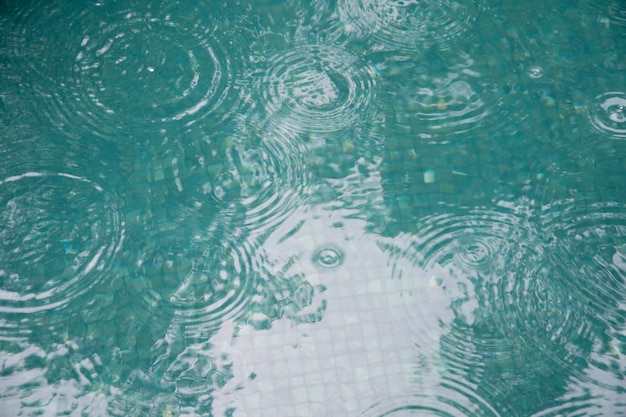 Surface de l'eau dans la piscine avec des gouttes de pluie