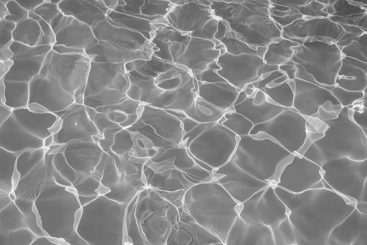 Photo surface de l'eau grise avec des reflets lumineux du soleil eau noire et blanche dans le fond de la piscine