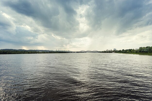 Surface de l'eau avec ondulations et reflets des rayons du soleil avec vue sur le fleuve Dnipro