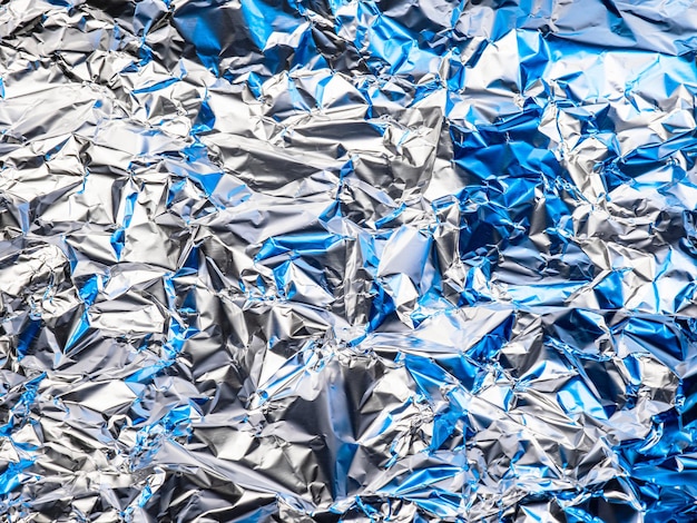 Photo la surface de la feuille est froissée il y a une lumière bleue reflétant la lumière et l'ombre et scie l'argent