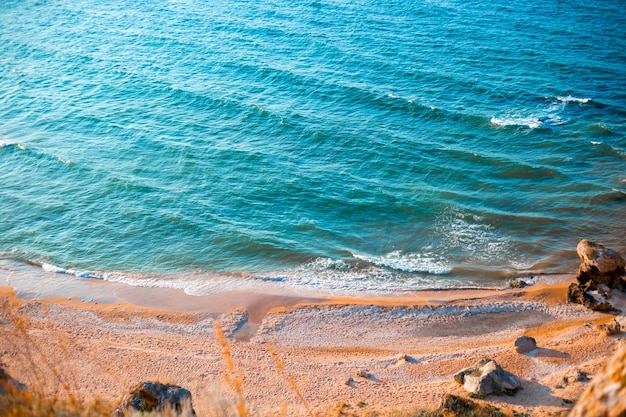 surface de la mer bleue avec des ondulations sur l'eau et vue de dessus du rivage sablonneux Voyages et tourisme