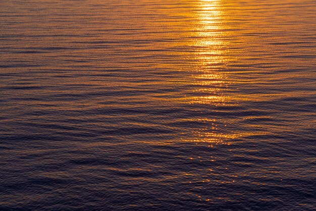 Surface de la mer avec des vagues aux couleurs du lever du soleil