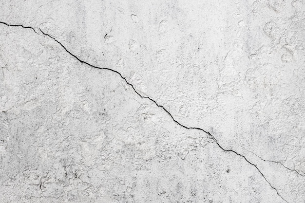 Surface de mur en béton fissuré avec de la peinture blanche pour le fond