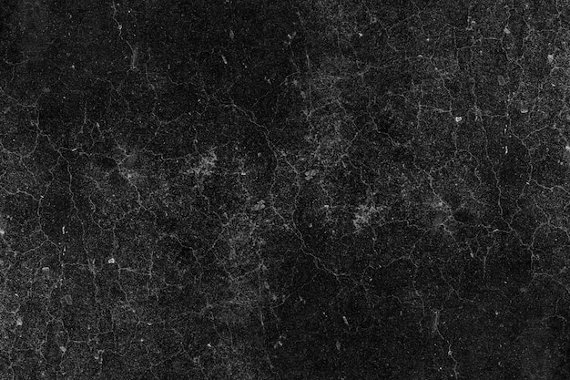 Surface de mur en plâtre de béton foncé fissuré avec une texture grunge lourde pour le fond