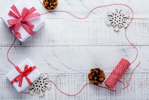 Surface de Noël avec ruban rouge, jouets, coffrets cadeaux et pommes de pin sur une vieille table de surface en bois blanc. Mise au point sélective.