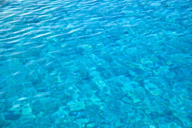 Surface de plan rapproché d'eau claire bleue avec de petites vagues d'ondulation dans la piscine.