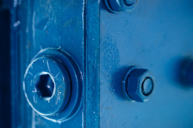 Surface rugueuse en métal bleu avec vis et écrous