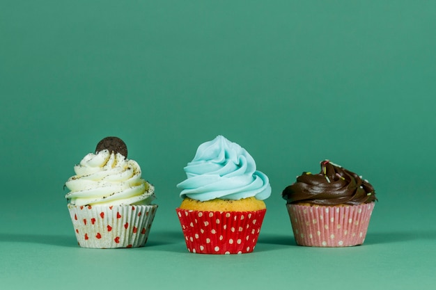 Photo surface verte avec trois petits gâteaux savoureux