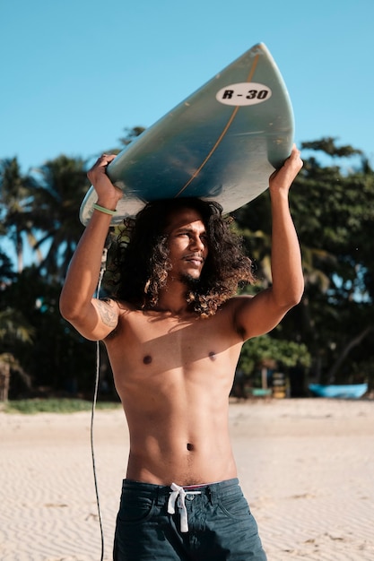 Surfer homme assis à la planche de surf sur la plage de sable