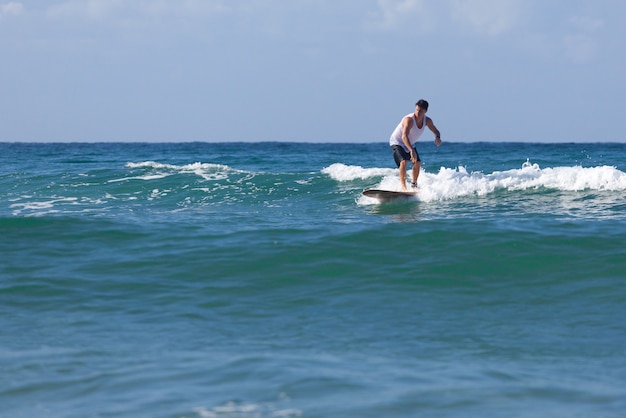 Surfer sur le longboard chevauche une vague dans la mer