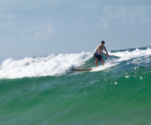 Surfer sur le longboard chevauche une vague dans la mer