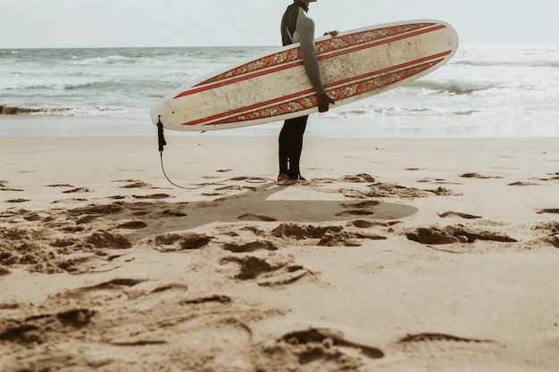 Surfer portant une planche de surf à la plage