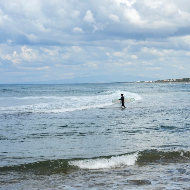 Surfeur avec la combinaison de plongée en mer bleue avec sa planche de surf