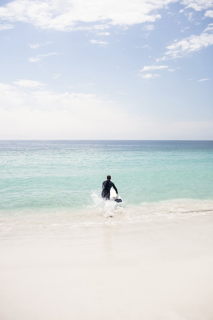 Surfeur courant vers la mer avec une planche de surf