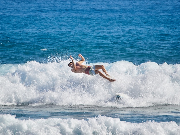 Le surfeur dans la vague disparaît et tombe de la planche de surf.