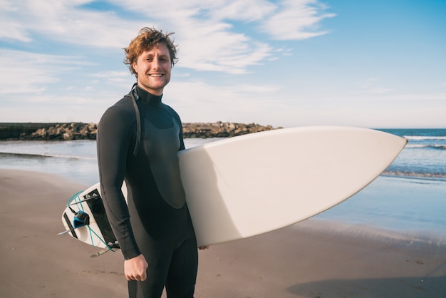 Surfeur debout dans l'océan avec sa planche de surf.