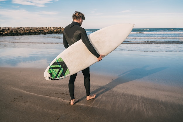 Surfeur entrant dans l'eau avec sa planche de surf.