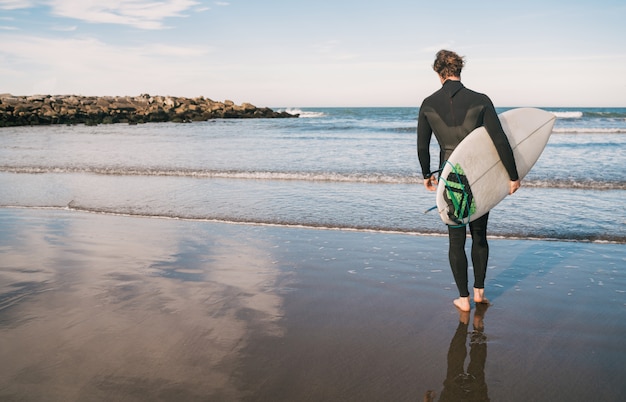 Surfeur entrant dans l'eau avec sa planche de surf.