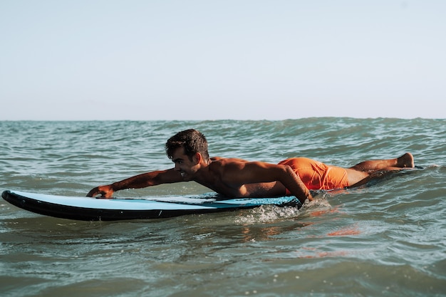 Surfeur masculin surfant sur de petites vagues