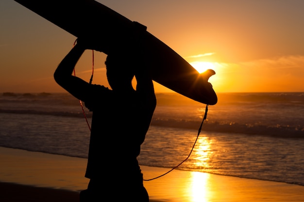 Surfeur et planche au soleil couchant