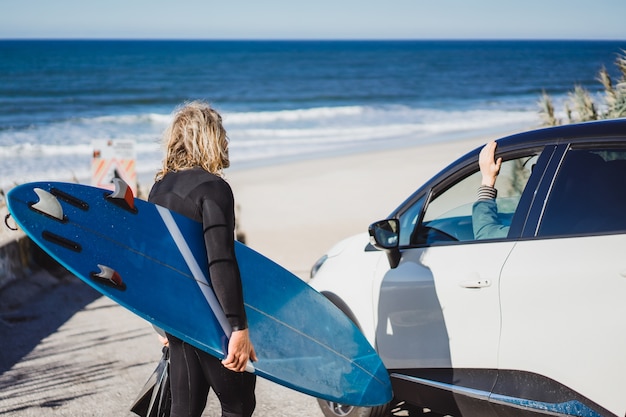 Un surfeur avec une planche de surf communique avec des amis par des surfeurs.