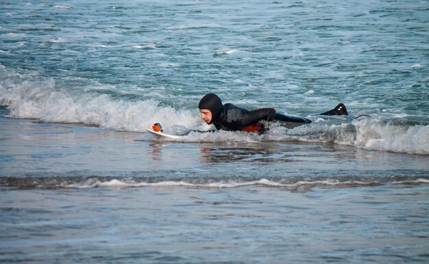 Le surfeur se tire dans l'eau avec une planche de surf. Selfie dans l'eau