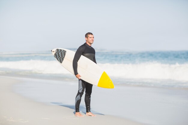 Surfeur tenant une planche de surf sur la plage