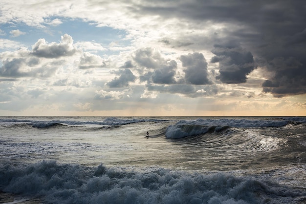 Les surfeurs chevauchent les vagues de la mer au coucher du soleil