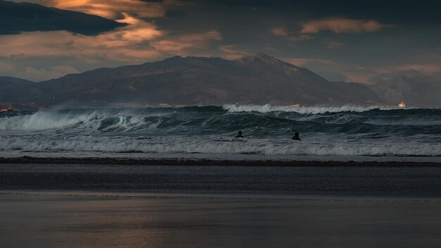 Surfeurs dans la mer profitant des vagues dans un magnifique coucher de soleil