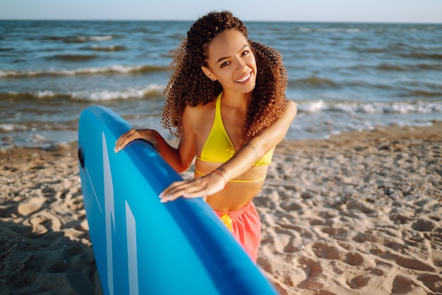 Une surfeuse se promène avec une planche sur la plage de sable Extreme sport Travel week-end lifestyle