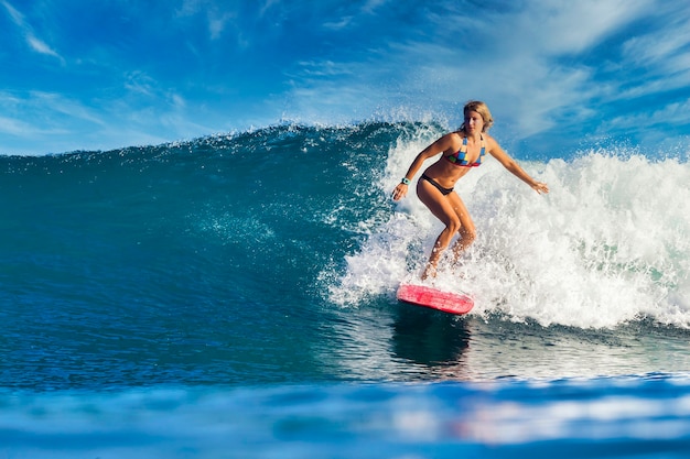 Surfeuse sur une vague bleue à la journée ensoleillée