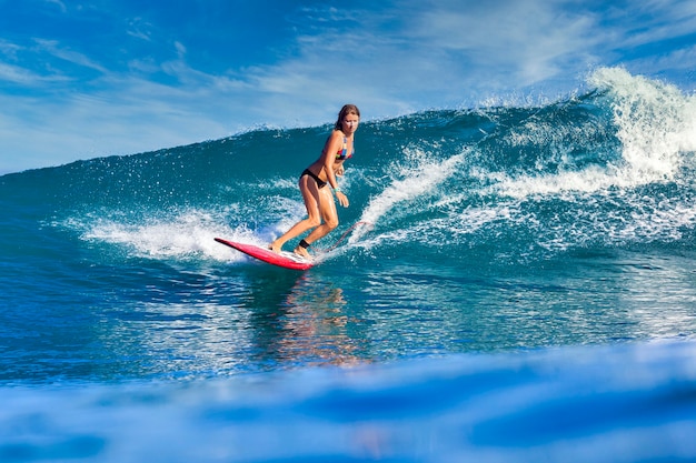 Surfeuse sur une vague bleue à la journée ensoleillée