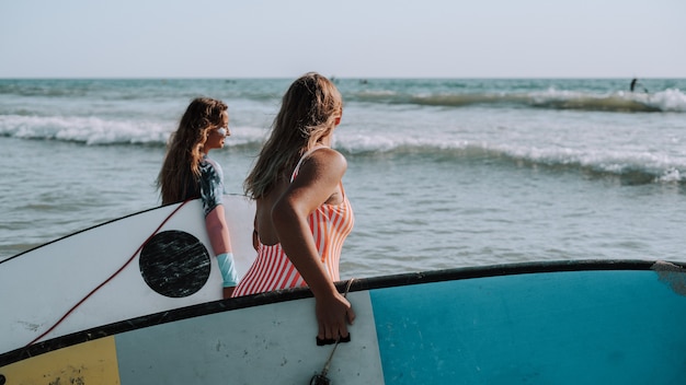 Surfeuses tenant leurs planches de surf et marchant vers la mer