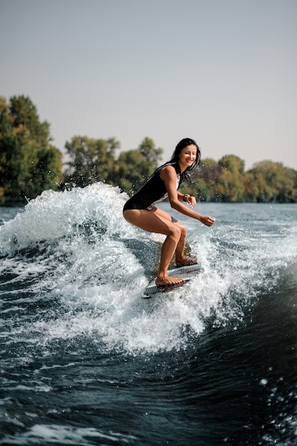 Surfgirl souriant sur une planche de surf près du bord de mer