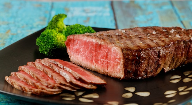 Surlonge de boeuf rare rôti en tranches avec brocoli sur plaque.