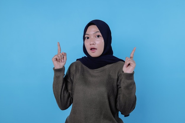 Surprenante femme asiatique avec son doigt pointé isolé sur fond de bannière bleu clair