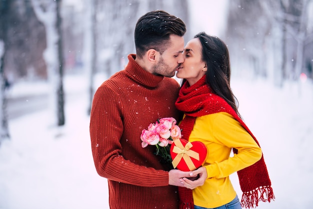 Surprenez avec amour le jour de la Saint-Valentin. Beau jeune homme donne un cadeau en vacances pour sa belle petite amie