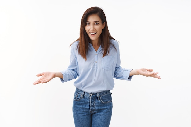 Surpris détendue et décontractée belle femme brune caucasienne en train de rire, expliquer l'accord facile, écarter les mains sur le côté avec insouciance, rire arrogant, ne pas s'inquiéter des problèmes de personne, se tenir debout sur un mur blanc