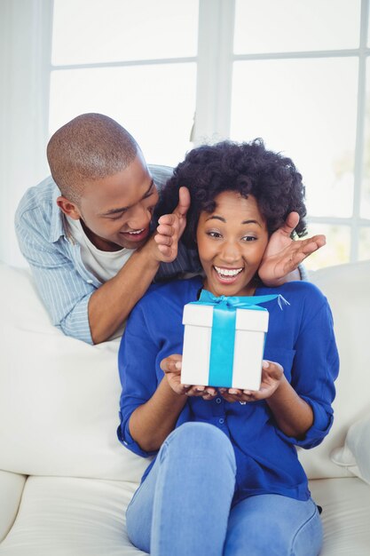 Surpris femme regardant cadeau sur ses mains sur le canapé