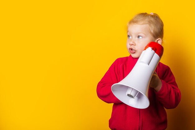 Surpris fille tenant un mégaphone sur un fond jaune vif.