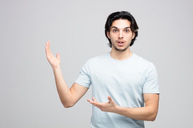 surpris jeune bel homme regardant la caméra montrant les mains vides isolé sur fond blanc