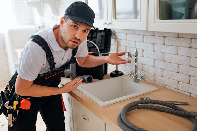 Surpris le jeune homme regarde la caméra et pointe sur l'évier dans la cuisine