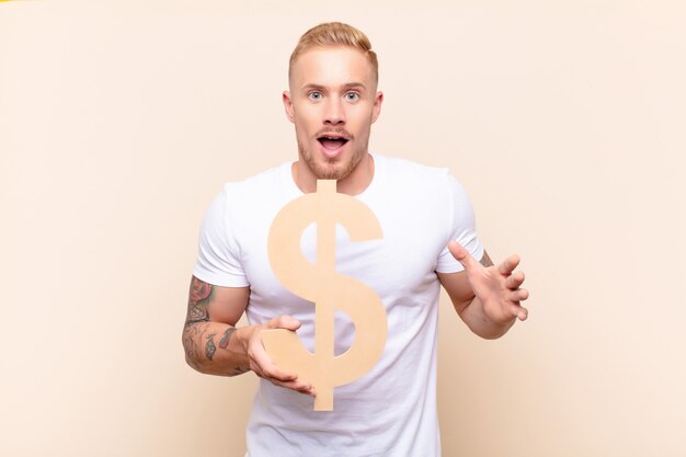 surpris jeune homme tenant le symbole de l'argent pour former un mot ou une phrase